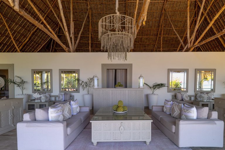 Lounge im Zawadi Hotel Restaurant Drift Wood mit zwei beigefarbenen Sofas, Holzdach und großem Kronleuchter