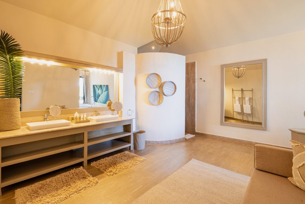 Helles Badezimmer im Zawadi Hotel mit zwei weißen Waschbecken, großem Spiegel