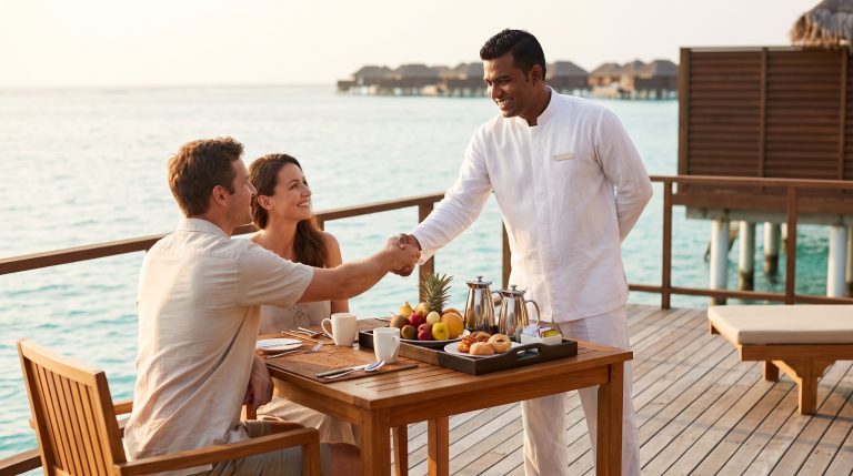 Gast bedankt sich beim Butler auf der Terrasse einer Wasservilla im Indischen Ozean