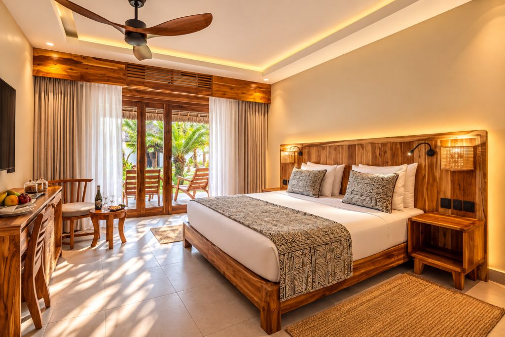 Deluxe Family Garden View Room mit großem Doppelbett, Holzmöbeln und Terrasse mit Palmen in Sansibar