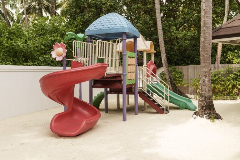 Kinderspielplatz im Sun Siyam Vilu Reef mit roten, grünen und blauen Rutschen und tropischem Grün im Hintergrund