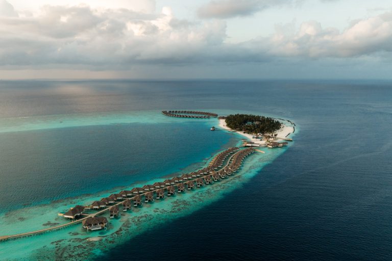Vogelperspektive auf Sun Siyam Vilu Reef Malediven mit Holzvillen und Strohdächern über türkisfarbener Lagune