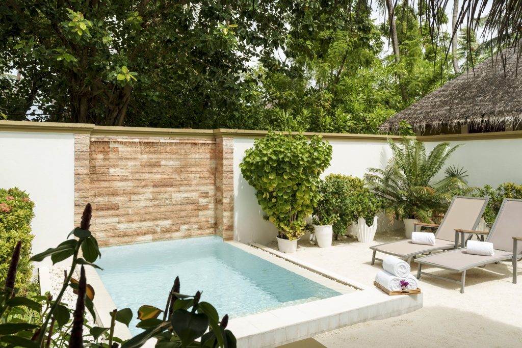 Privater Außenbereich im Sun Siyam Vilu Reef mit kleinem Pool, cremefarbener Mauer und tropischen Pflanzen auf den