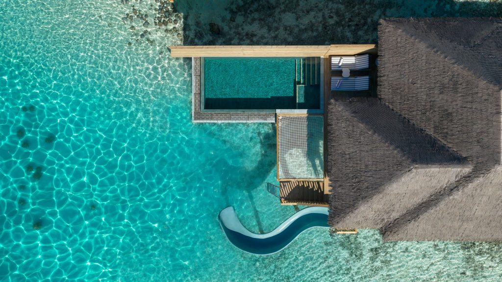 Luftaufnahme der Ocean Signature Villa mit privatem Pool, Holzterrasse und Wasserrutsche im türkisen Meer