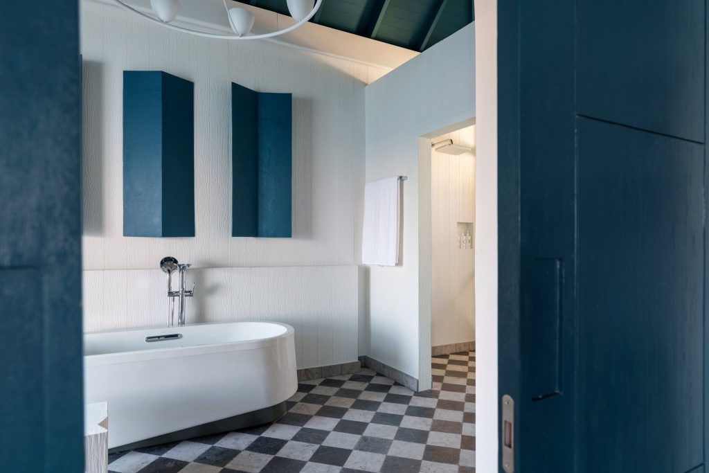 Badezimmer mit freistehender weißer Badewanne, blauem Wanddekor und Schachbrettfliesen im Ocean Signature Villa